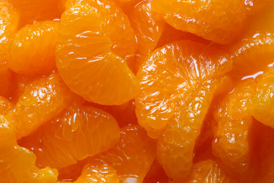 Mandarin segments in juice background backdrop. Tinned fruit food concept.