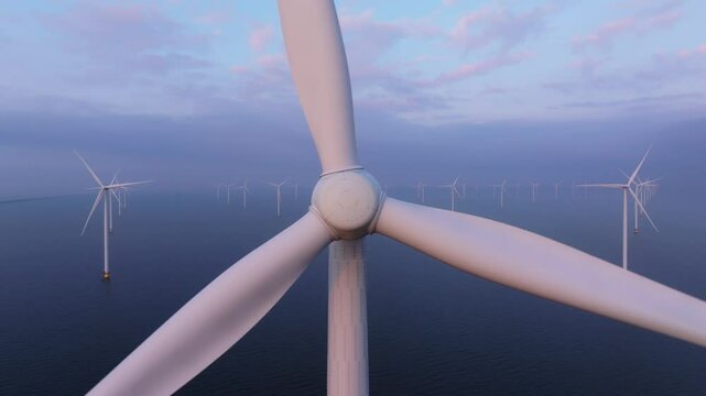 Drone capturing close up of spinning rotor blades offshore turbine. Aerial drone video