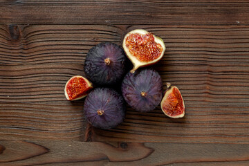 Whole and cut fresh ripe figs on wooden table. Top view