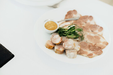 Cured meat platter served with mustard and fresh greens at a dining table
