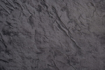 Dark textured surface resembling stone with natural patterns and details