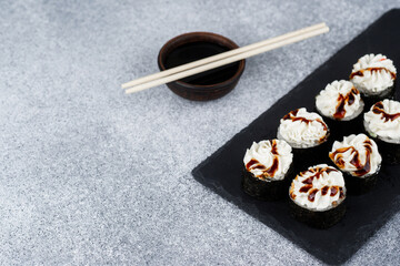 Delicious sushi rolls served on a slate plate with soy sauce and chopsticks