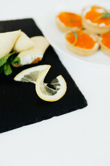 Delicious savory dish with lemon and sweet dessert slices on black slate