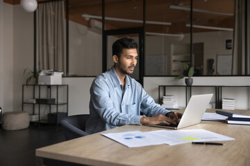 Authentic Indian businessman in his 30s stays busy with analysis and tech development. Successful...
