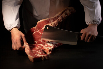 Butcher cutting loin on black background