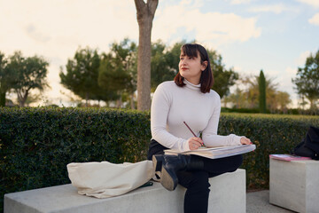 Young artist sketching outdoors in a park finding inspiration in nature