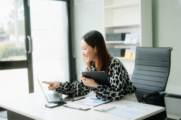 Asian business woman are delighted and happy with the work they do on their tablet, laptop and...