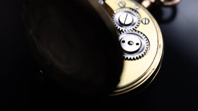 Swiss antique gold pocket watch. View of the inside mechanism. 1900s Swiss cylinder escapement ladies 14 carat gold watch with an engraving. On dark background