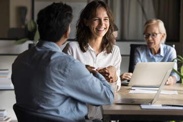 Executive business lady laughs enjoying project discussion with office colleague, discuss business strategy and financial matters engage in consultation, review documents, collaborate on presentation