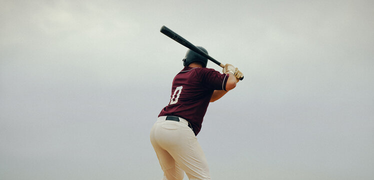 Baseball player poised to hit the pitch, showing concentration and readiness at the batter's box