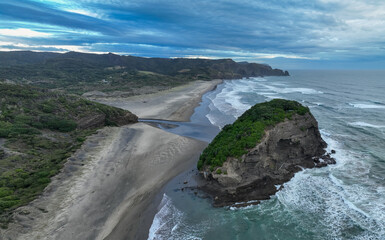 Aerial view of Bethells Beach, Auckland, New Zealand, showcasing its black sand, rugged cliffs, and...