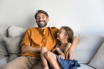 Carefree family fun. Candid laughing middle aged dad tween child daughter relaxing messing on soft...