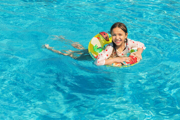 Little girl having fun on family summer vacation in tropical hotel resort. Little girl enjoying on inflatable ring  at pool.