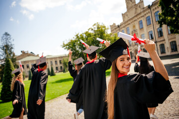 Rear photo of company groupmates students hold diplomas mortarboard gown graduate college building...