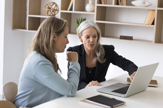 Professional consultation. Experienced senior businesswoman bank manager financial advisor meet with female client customer in work office give advice support explain contract details using notebook