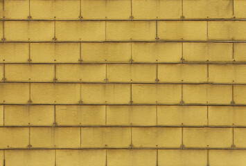 Yellow wall tiles creating repeating pattern with rivets