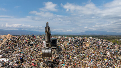 Bulldozer working on massive lanfill waste site with mountain background, Heavy machinery manage plastic waste at larg garbage dump, Excavtor at landfill global waste crisis concept.