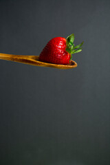 Fresas en una cuchara fondo gris