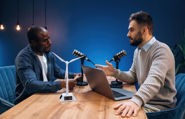 Side view, talking. Two radio presenters recording an audio broadcast in a studio