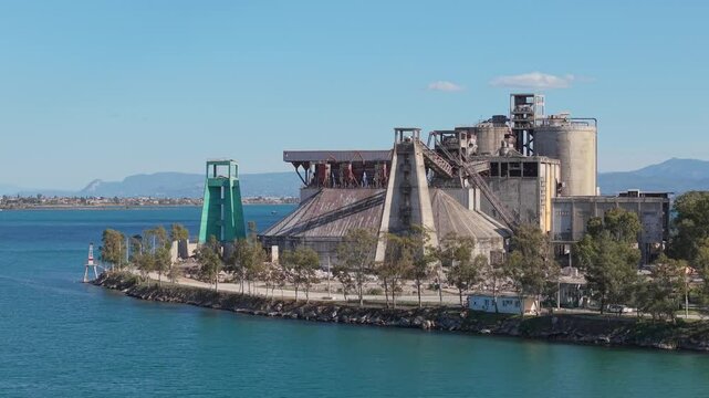 Cinematic orbit footage of an abandoned cement factory in Chalkida, Greece. Industrial decay, concrete textures, and raw urban atmosphere in a dramatic setting