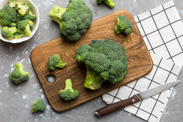 fresh green broccoli on wooden cutting board with knife. Broccoli cabbage leaves. light background....