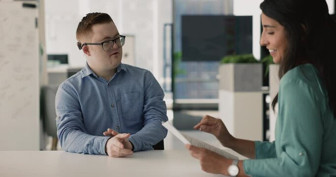 Inclusive company HR manager woman hiring young down syndrome candidate man, shaking hand of happy positive applicant after successful interview, holding paper resume document