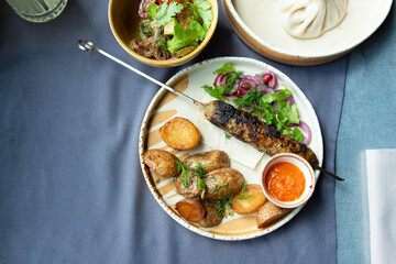 Georgian lula kebab plate. Bbq skewer, traditional barbecue dish with baked potatoes, sauce