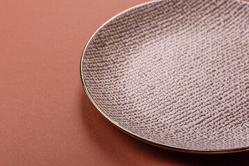 Empty ceramic plate on a monochrome brown background