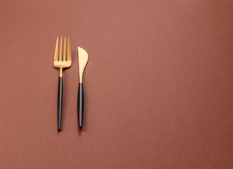 Knife and fork, cutlery on a brown dining table
