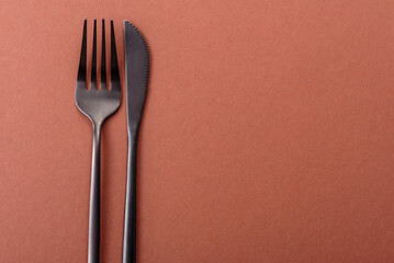 Knife and fork, cutlery on a brown dining table