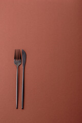 Knife and fork, cutlery on a brown dining table