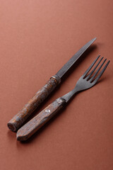 Knife and fork, cutlery on a brown dining table