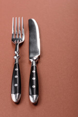 Knife and fork, cutlery on a brown dining table