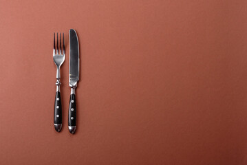 Knife and fork, cutlery on a brown dining table