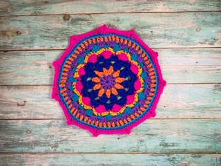 Crocheted mandala doily on wooden background handmade decor art craft photo	