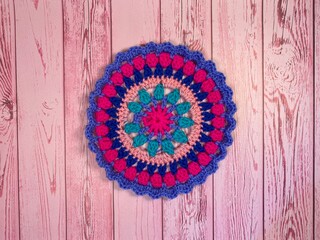 Crocheted mandala doily on wooden background handmade decor art craft photo	