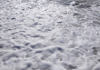 A serene beach at midday with gentle waves lapping the shore and clear blue skies inviting relaxation