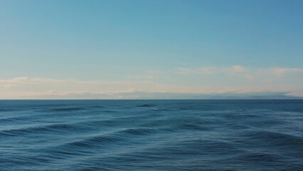 Obraz premium Serene view of a calm ocean at sunset, with the horizon line visible and clear blue skies. Ideal for relaxation or vacation photography.