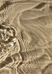 Water texture with shadows on sea beach sand