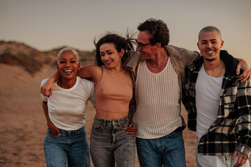 Happy friends walking together on beach at sunset, embracing friendship and joy