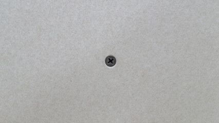 Black screw screwed into drywall close up