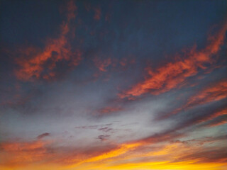 Dramatic sunset sky with vibrant orange and pink clouds against a dark grey backdrop.  Perfect for backgrounds, travel, or naturethemed projects. Evokes feelings of serenity and awe.