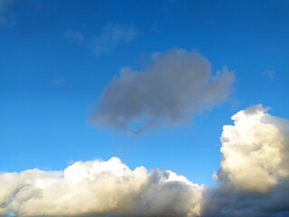 Obraz premium Blue sky with fluffy clouds. Ideal for backgrounds, travel, nature, or weather themes. Evokes freedom, peace, and possibility. Perfect for adding depth to designs.