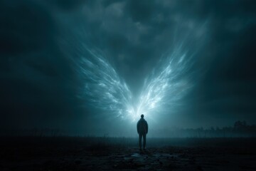 Fototapeta premium A solitary figure gazes up at ethereal light wings emerging from a dark, moody sky, creating a sense of wonder and surreal beauty, adding to the dramatic scene.