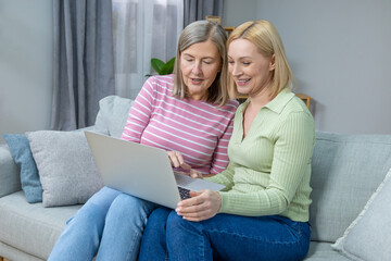 Two women looking old photos on laptop and looking happy and contented