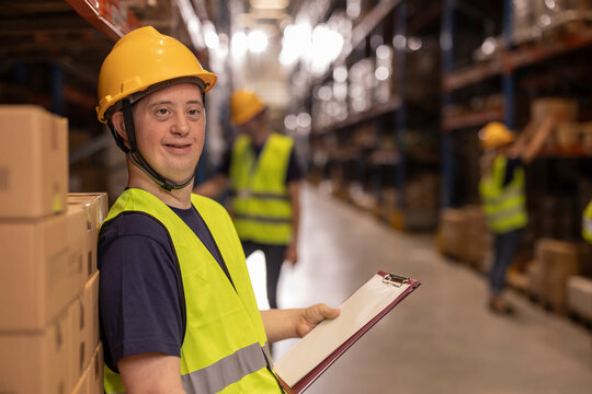 Warehouse worker with down syndrome holding clipboard and smiling