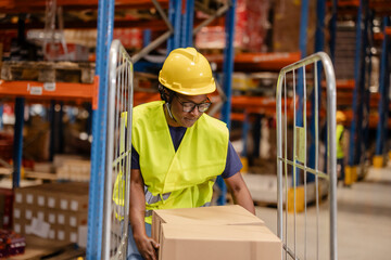 Female warehouse worker pushing trolley with cardboard boxes