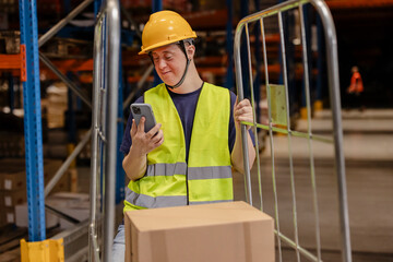 Warehouse worker with down syndrome using smartphone and pushing cart