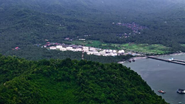 A daytime drone shot revealing Pertamina TBBM Manggis Bali, showcasing the city infrastructure surrounded by lush natural landscapes.
