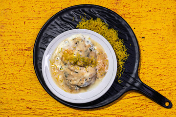 A flavorful Indian chaat dahi vada or dahi bhalla served with yogurt, tamarind chutney, and crispy toppings served on elegant black platter. Ideal for showcasing traditional cuisine and tasty snacks.